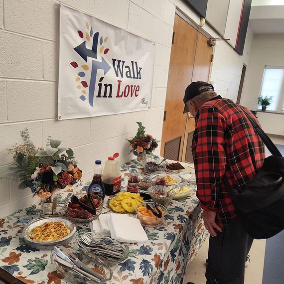 Man looks at a buffet table with food, under a banner that says 