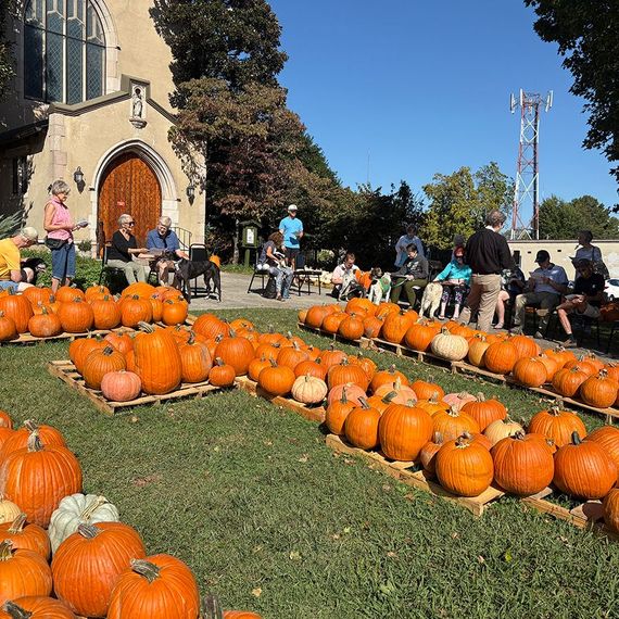 People at a pumpkin patch in front of a church. Pumpkins are arranged on pallets.