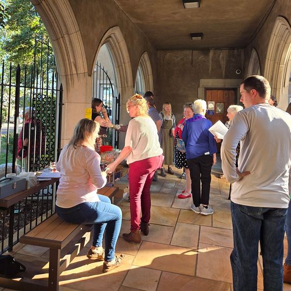 People socializing under a stone archway. Sunlight illuminates the scene.