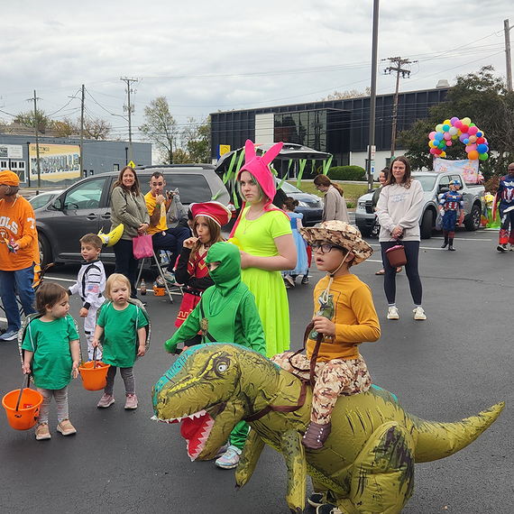 Halloween party with costumed children and adults in a parking lot.