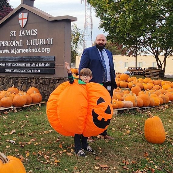 Man and child in pumpkin costume at a church pumpkin patch.