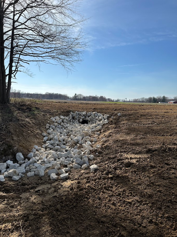 A stream filled with rocks is going through a field.