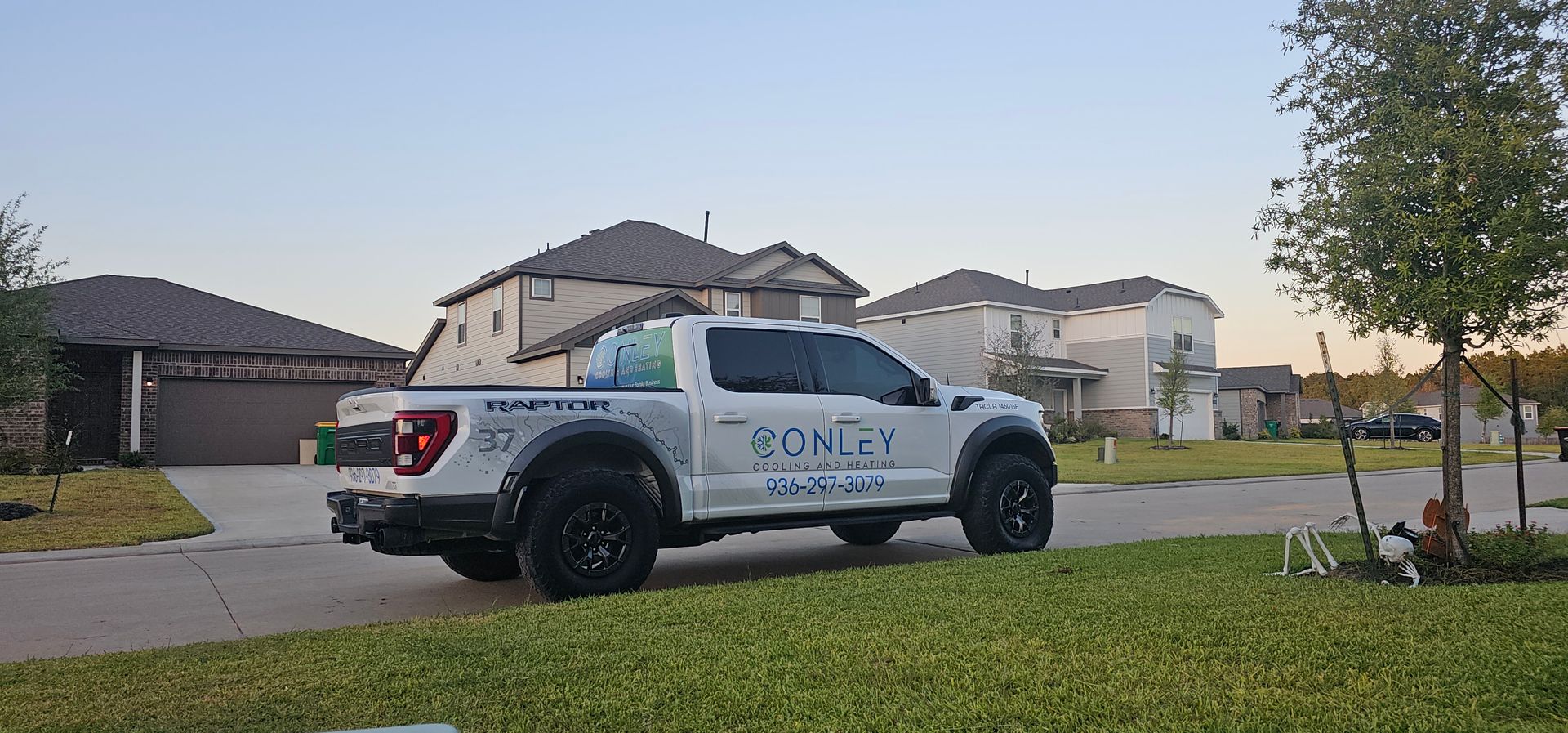 Two air conditioners are sitting next to each other in front of a brick wall installed by Conley Cooling and Heating.