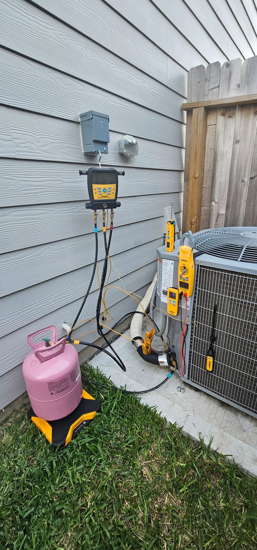 A propane tank is sitting on the side of a house next to an air conditioner by Conley Cooling and Heating.