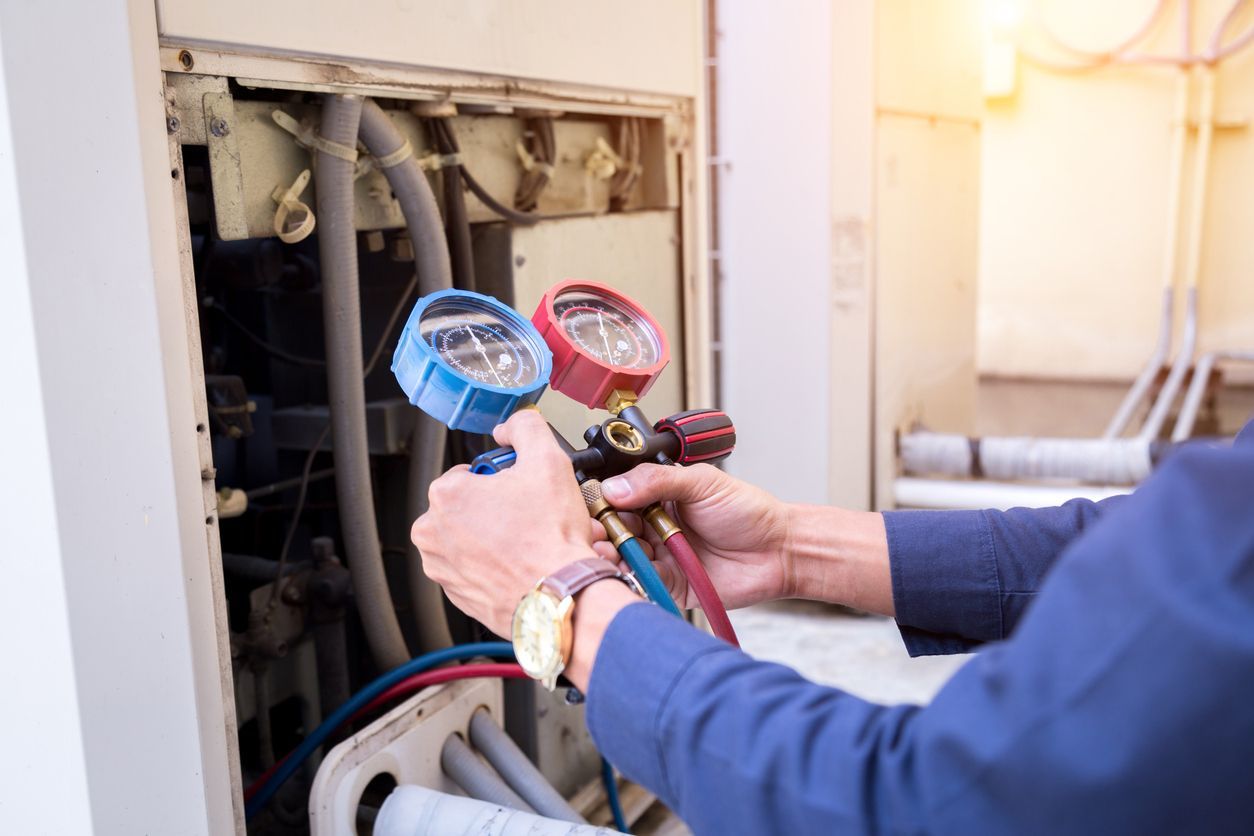 A Conley Cooling and Heating technician is working on an air conditioner with two gauges.