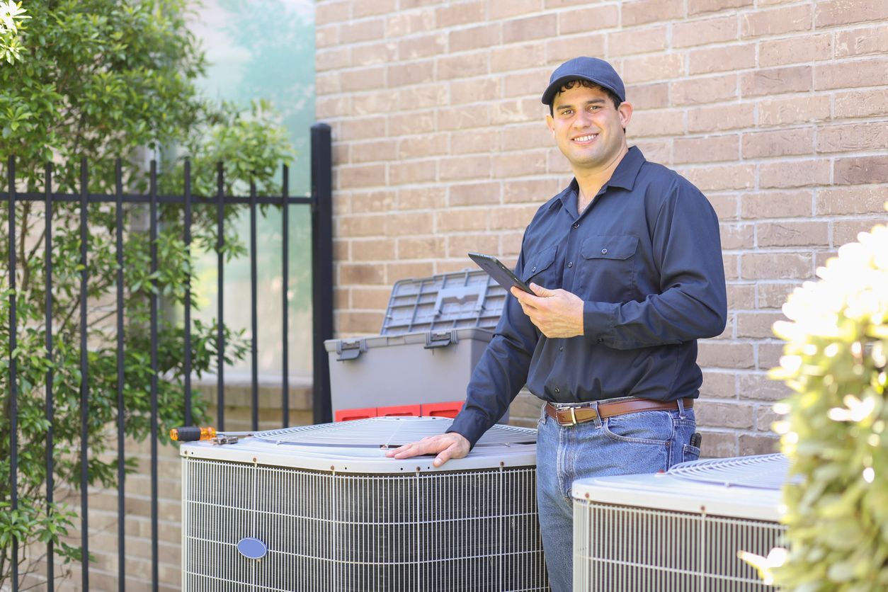 A Conley Cooling and Heating technician is standing next to two air conditioners in front of a brick building.