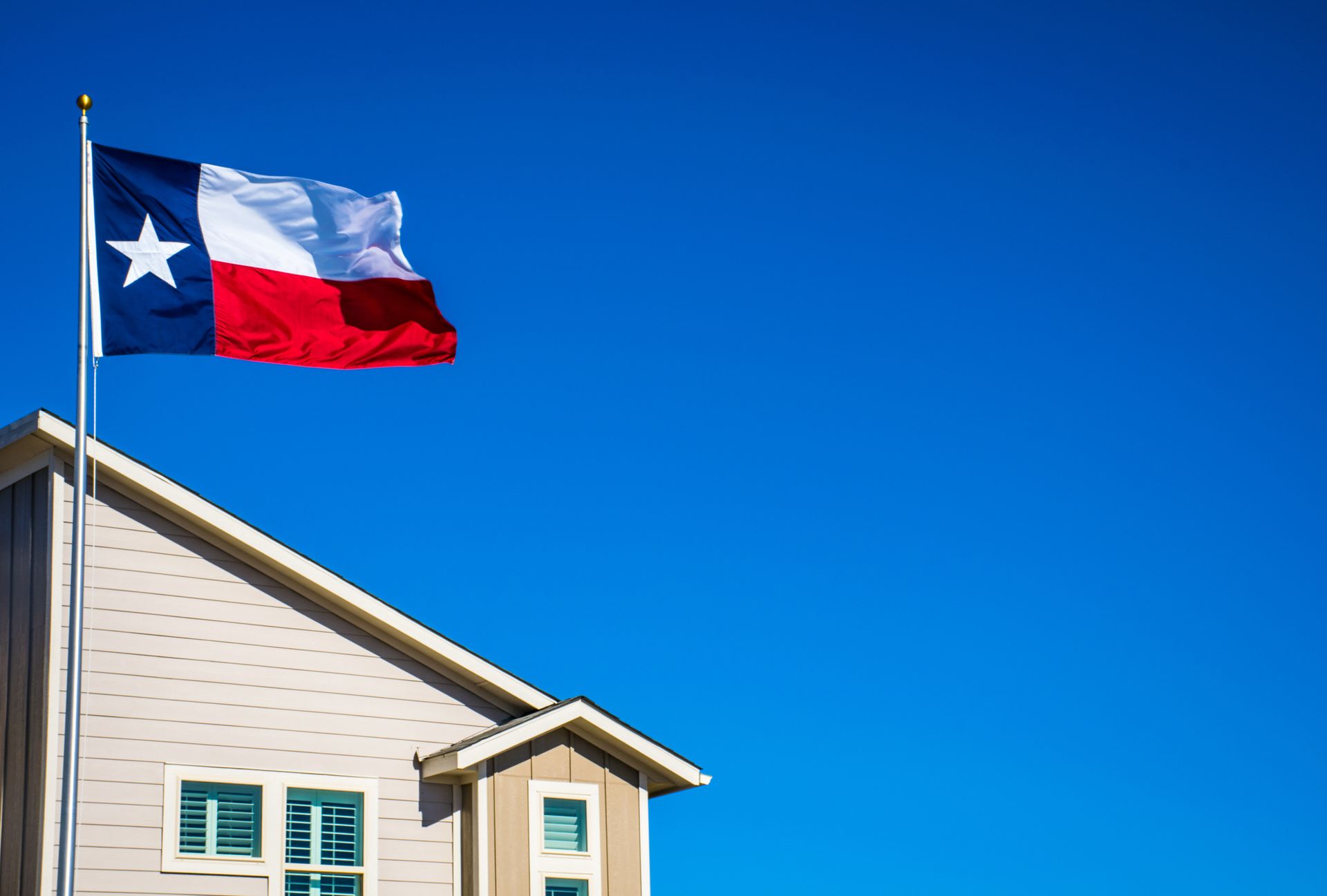 A texas flag is flying on top of a house.