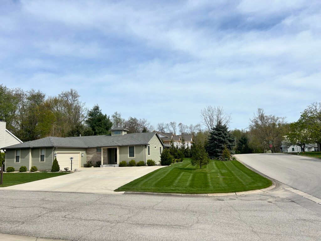 A house with a driveway and a lush green lawn in front of it.