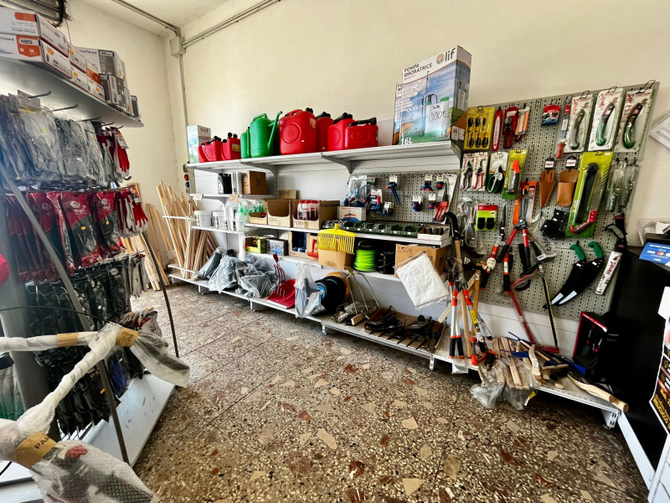 Scaffali pieni di vari utensili, ferramenta e articoli per la pesca all'interno di un negozio al dettaglio.