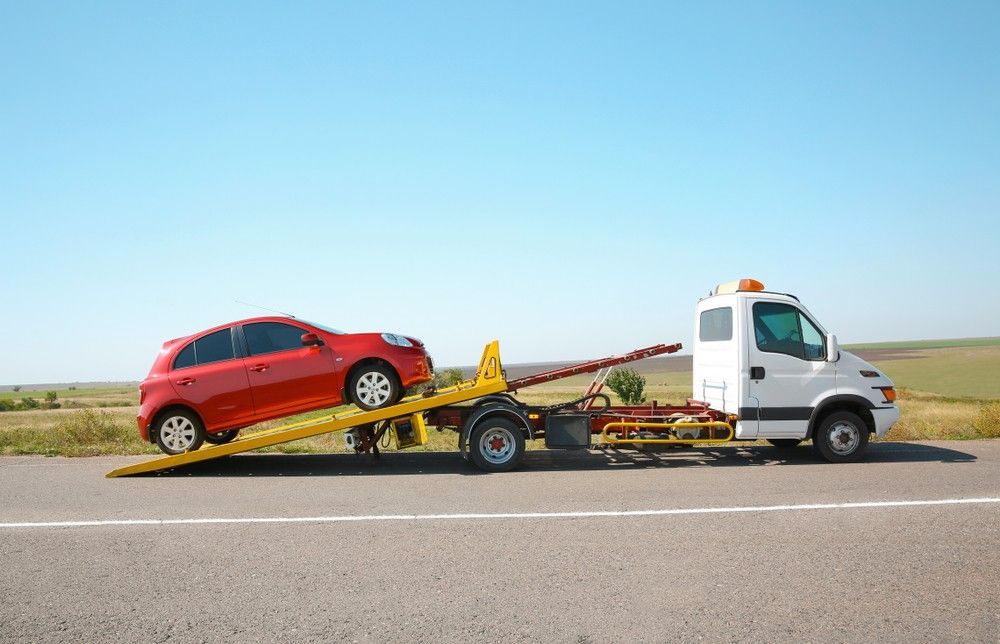 A Red Car is Being Towed by a Tow Truck on the Side of the Road — JEC Transport in Winnellie, NT