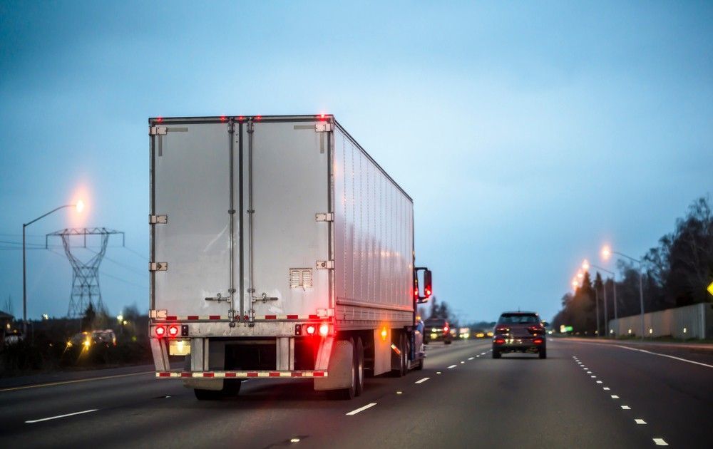 A Semi Truck is Driving Down a Highway at Night — JEC Transport in Winnellie, NT
