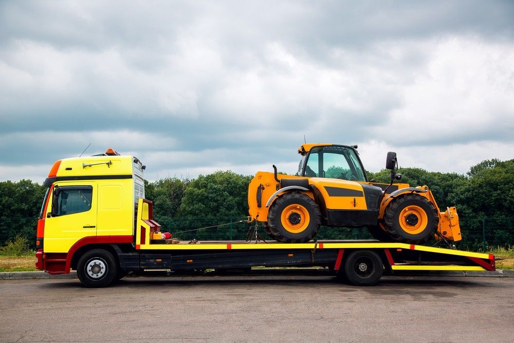 A Yellow Tow Truck is Carrying a Yellow Tractor — JEC Transport in Winnellie, NT