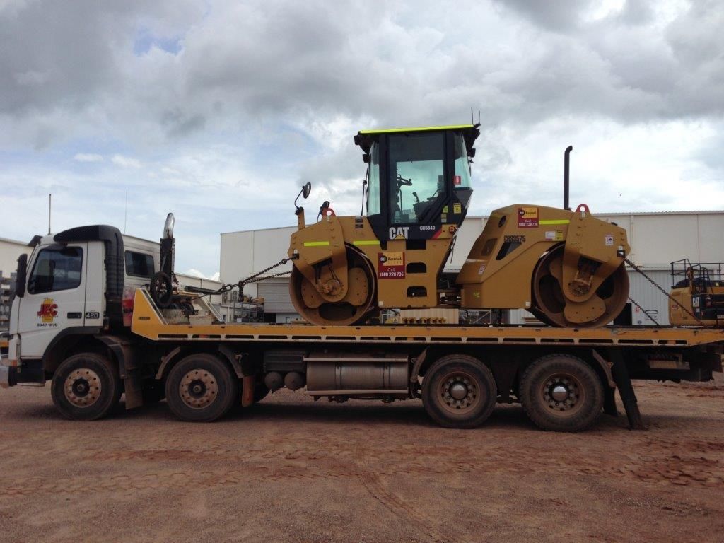 A Tow Truck With A Road Roller On Back