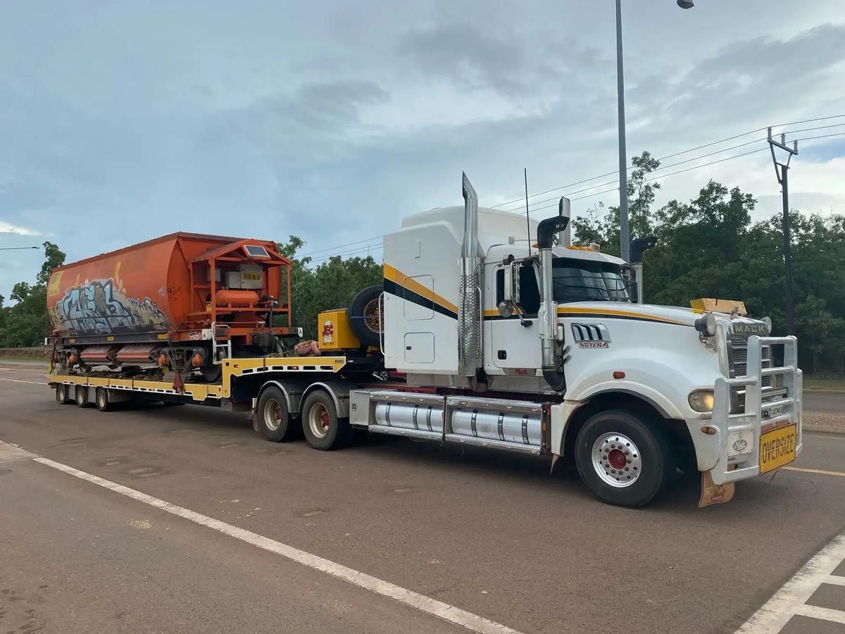 A Semi Truck is Towing a Train on a Flatbed Trailer — JEC Transport in Winnellie, NT