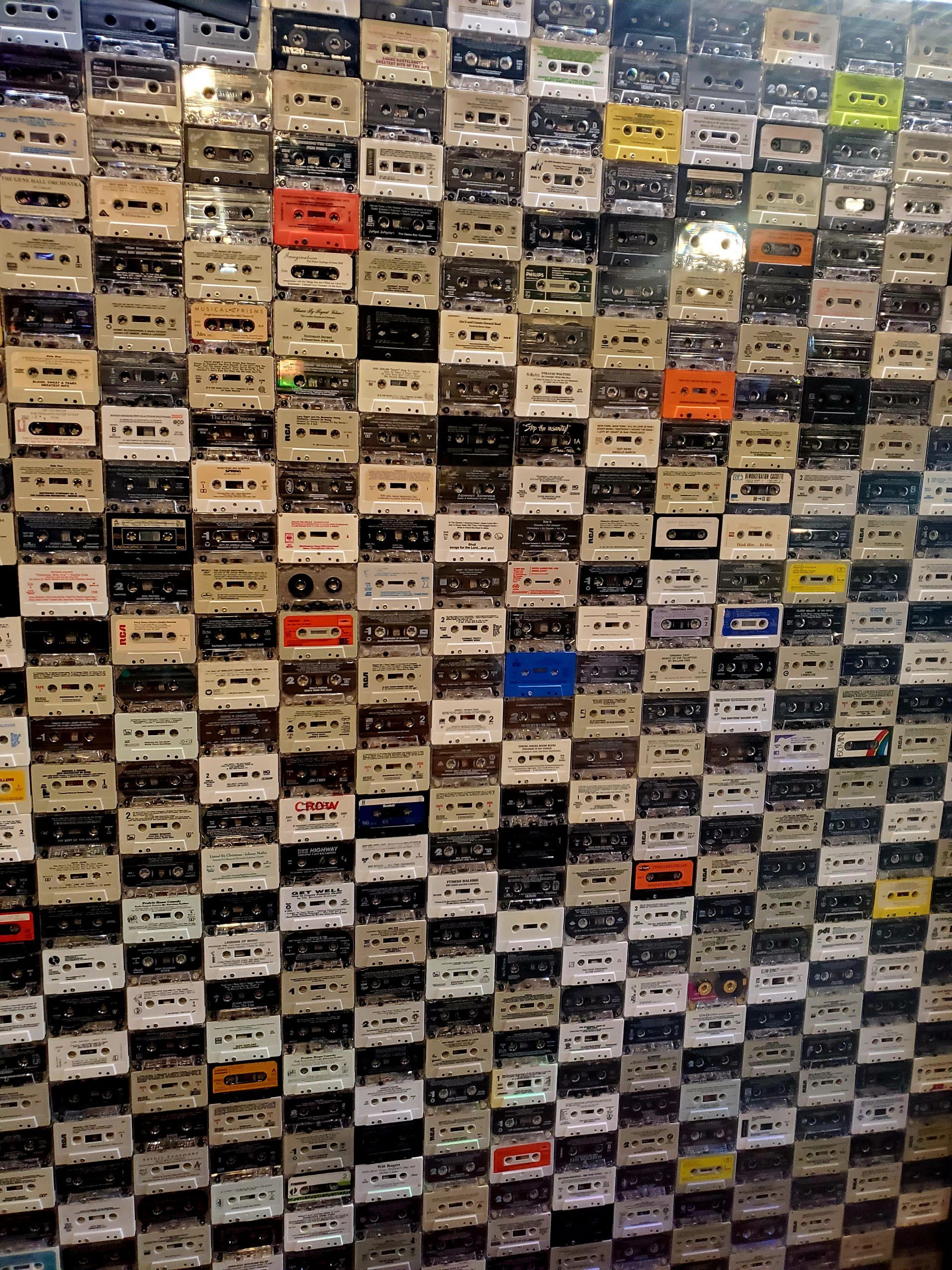 A wall filled with lots of cassette tapes of different colors