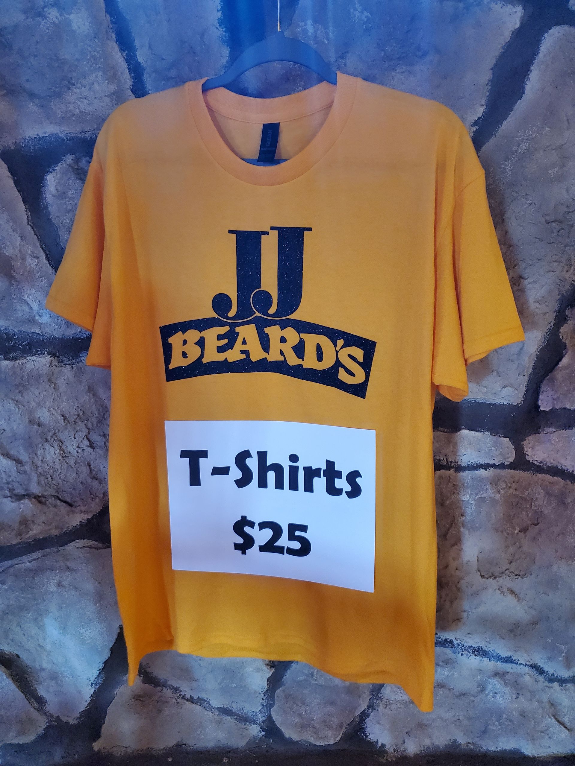 A yellow j.j. beards t-shirt is hanging on a hanger