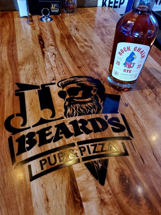 A bottle of whiskey sits on a wooden table at j.j. beard 's pub and pizza