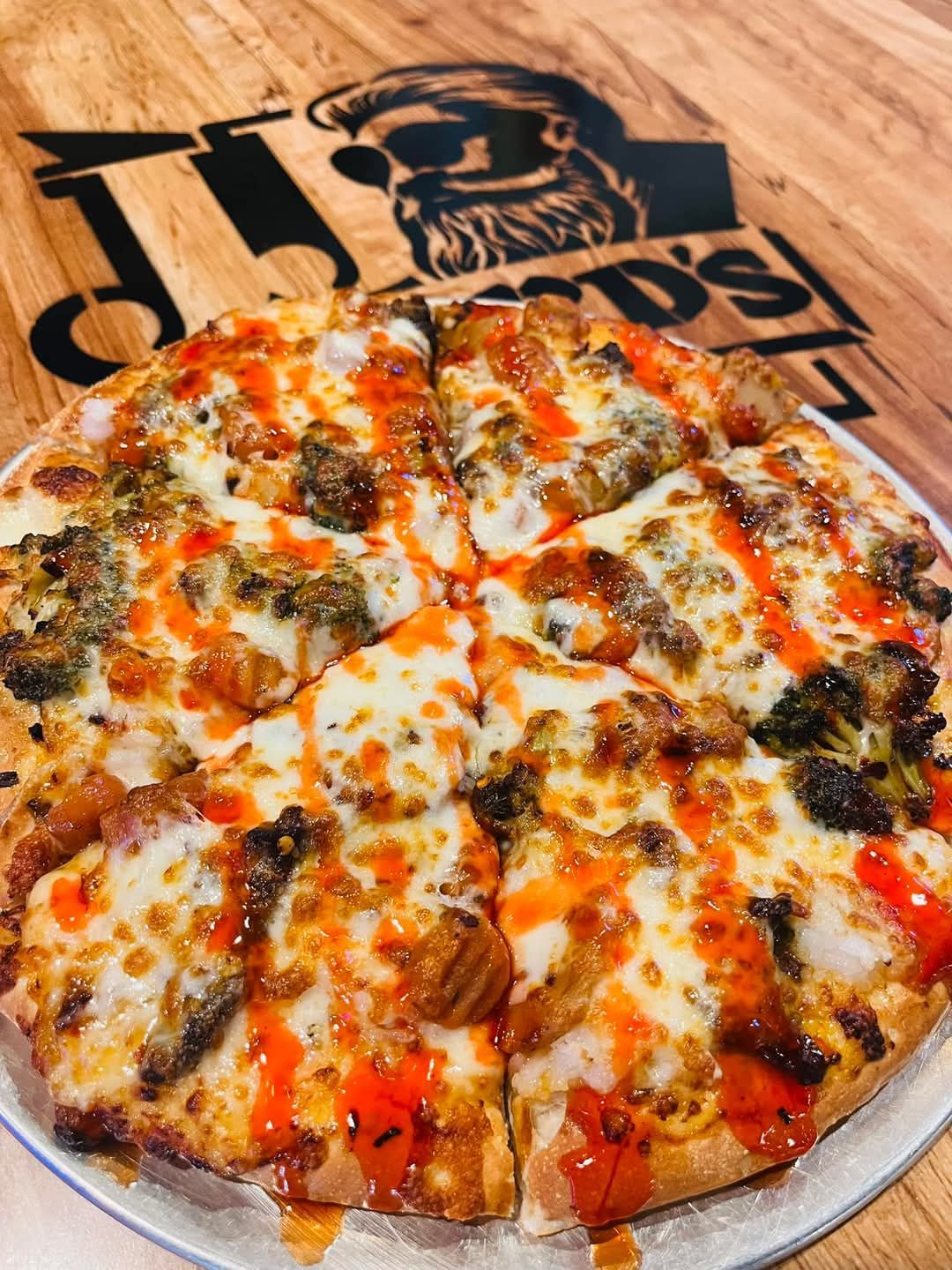 A pizza is sitting on a white plate on a wooden table.