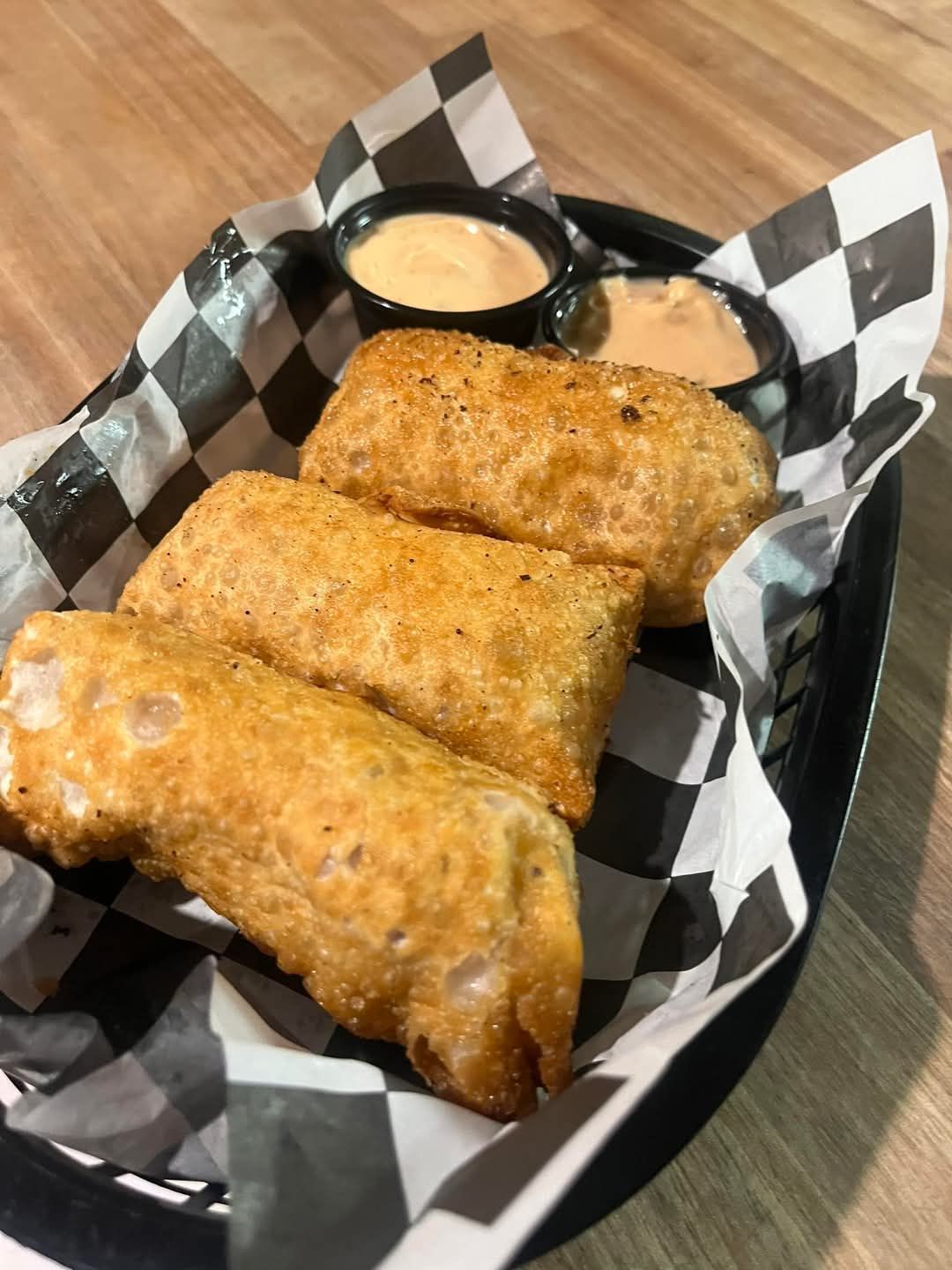 A basket filled with fried food and dipping sauces on a table.