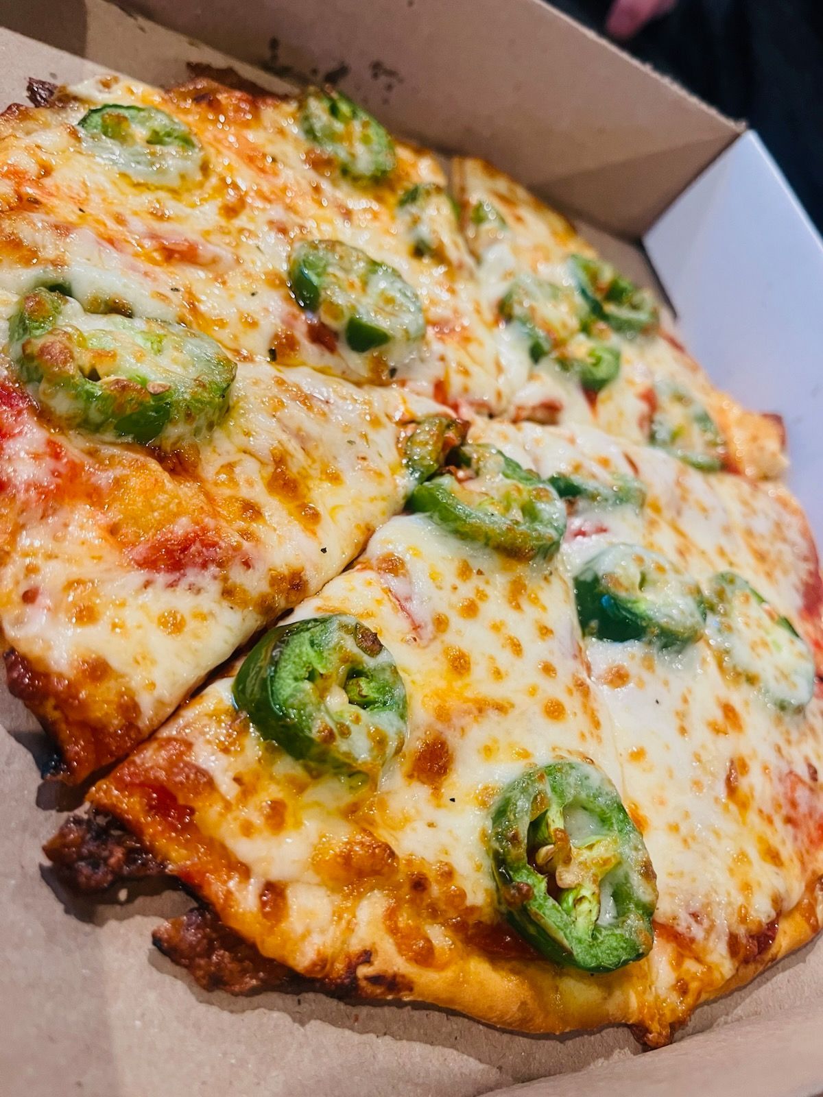 A pizza with jalapenos on it is in a box.