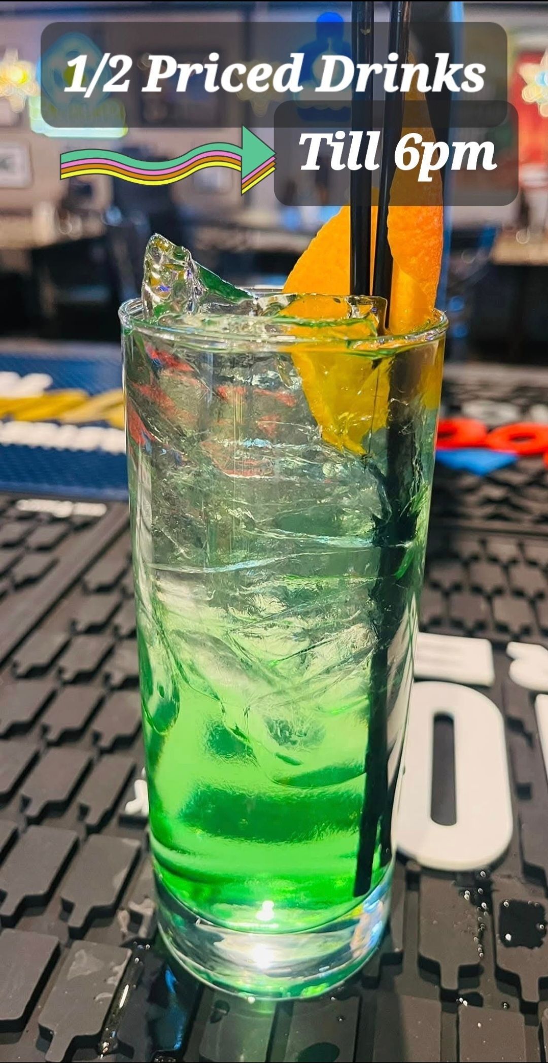 A glass of green liquid with a straw on a table.