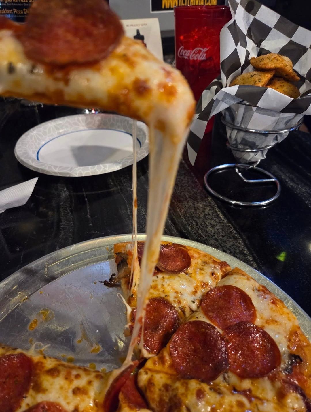 A pepperoni pizza with cheese being pulled out of it