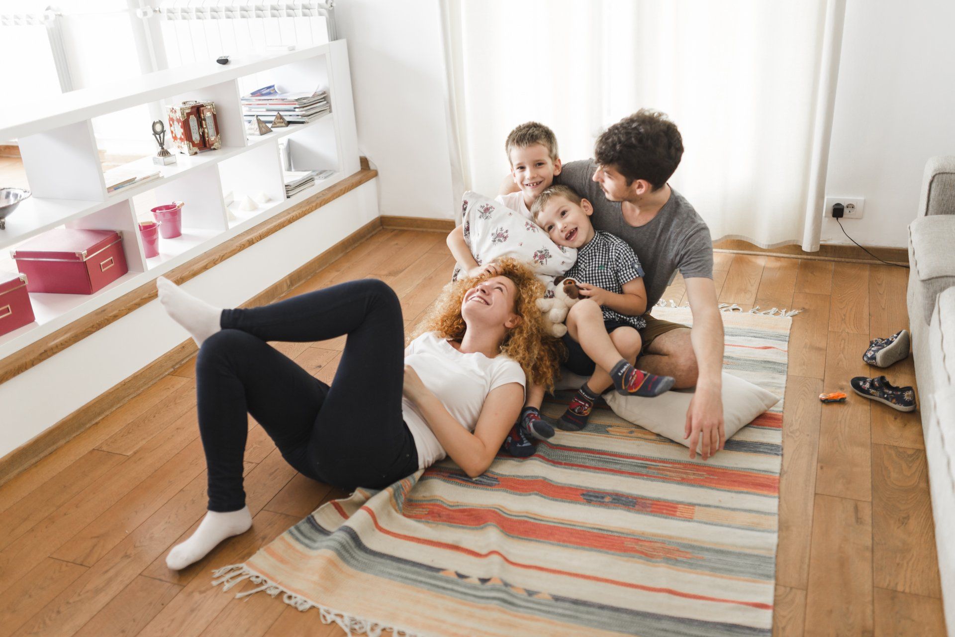 A family is laying on the floor in a living room.