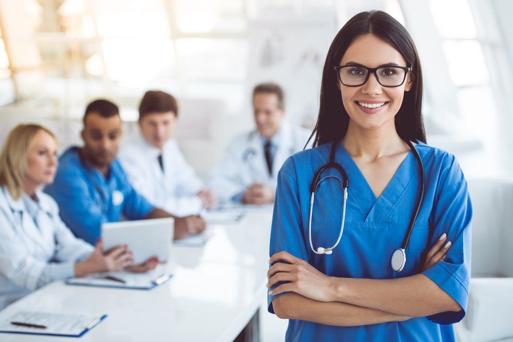 A female doctor is standing in front of a group of doctors.