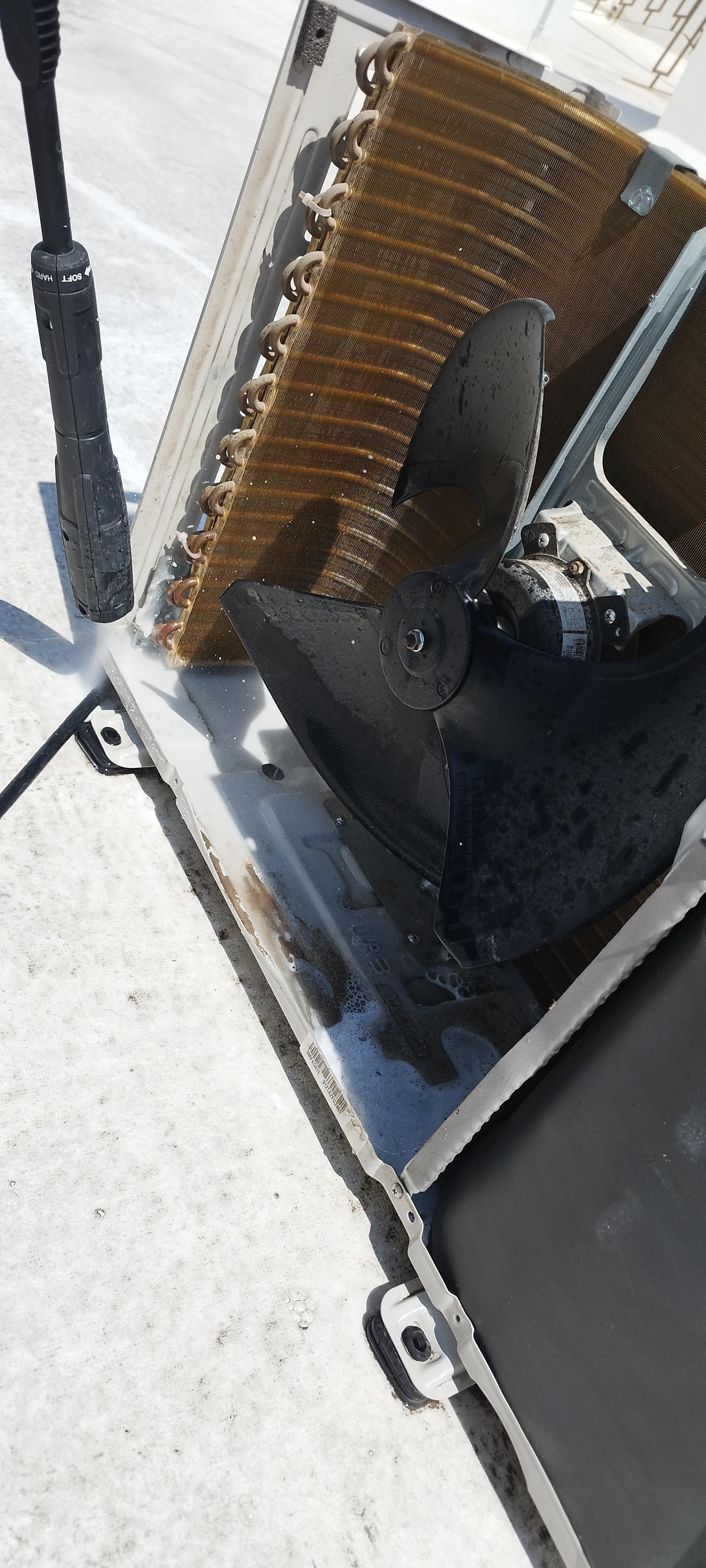 Vista desde arriba que muestra las bobinas de cobre y el conjunto del motor negro dentro de una unidad de aire acondicionado abierta.