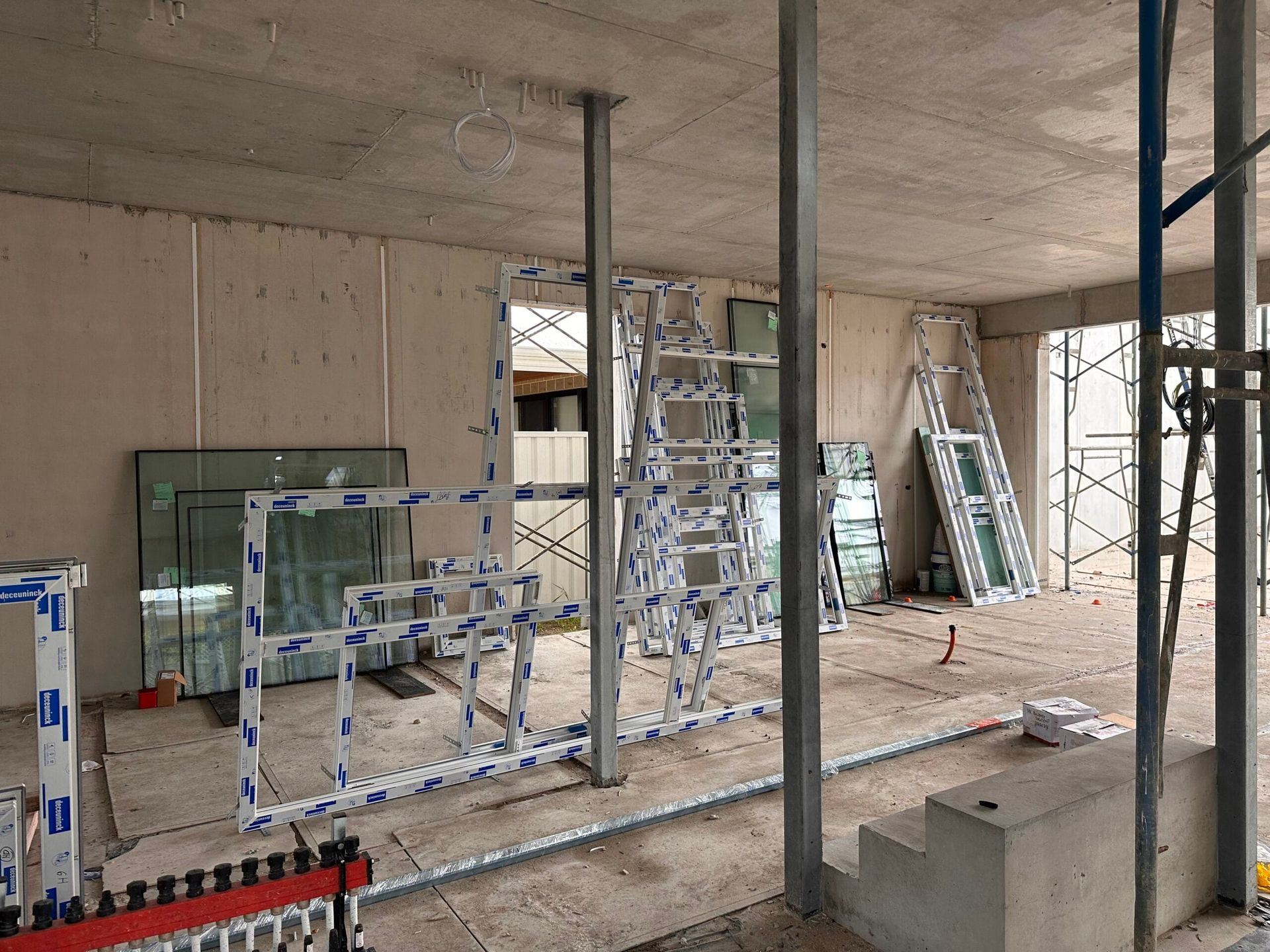 Construction site interior with window frames and supporting beams.
