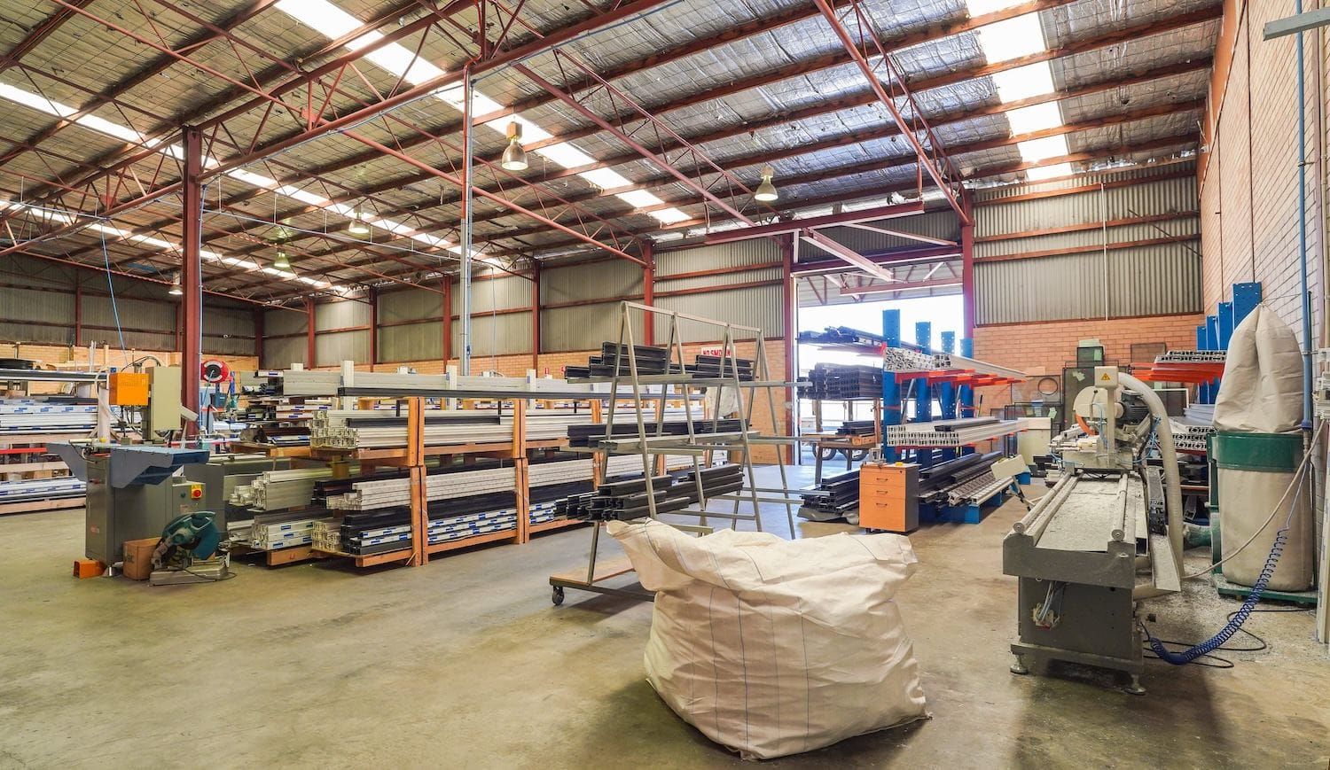 Warehouse interior with metal shelving, machinery, and open doorway.