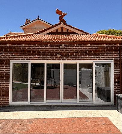 Brick building with white sliding glass doors, red tile roof, and a rooftop decorative bird.
