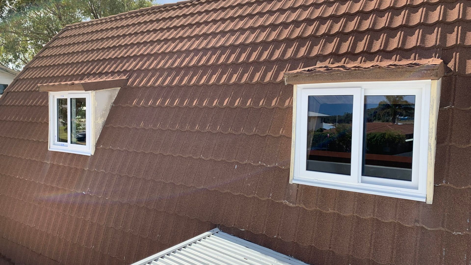 Brown tile roof with two white-framed windows.