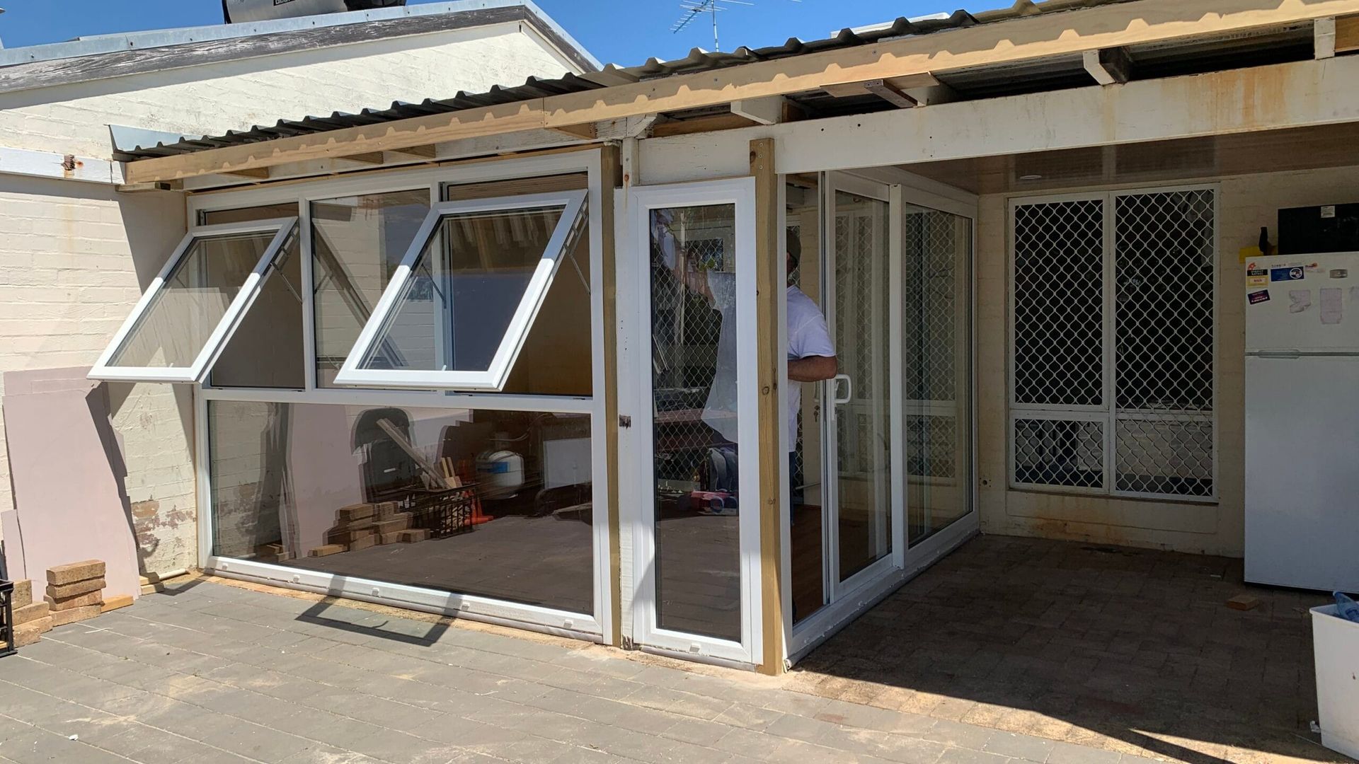 Outdoor enclosure with glass windows and doors; a person stands inside.