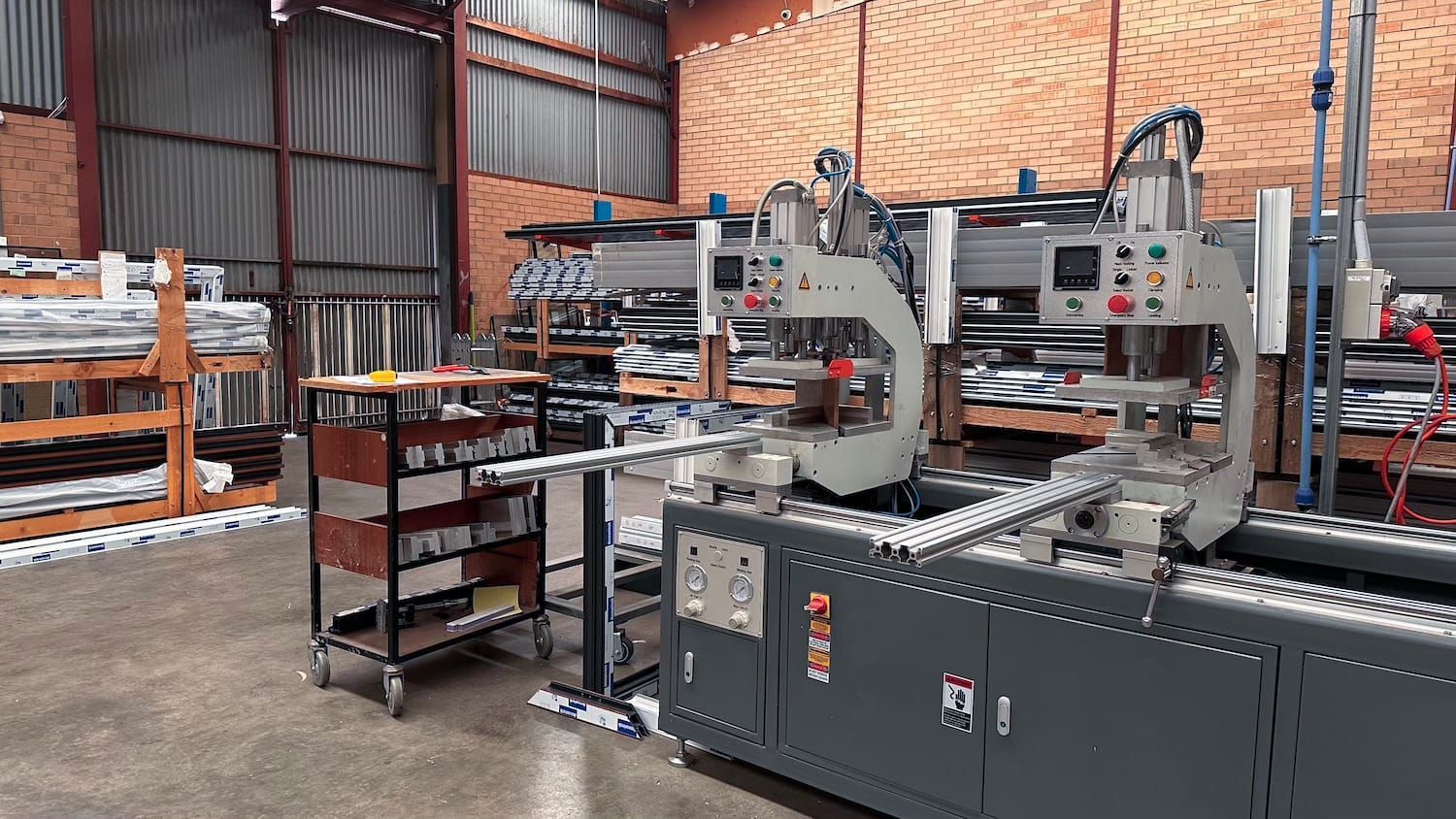 Factory interior with industrial machinery. Metal components on a large machine, with shelves and work areas.