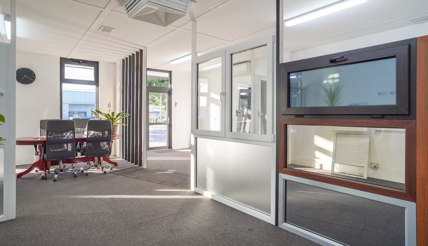 Office interior: meeting table, chairs, glass walls, fish tank, projector, and gray carpet.