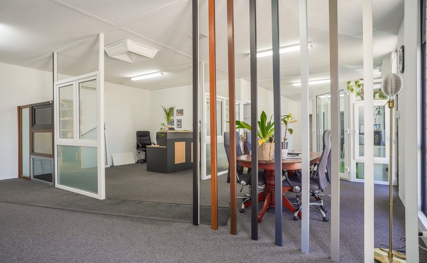 Interior of an office showcasing window frame samples, with a round table and chairs.