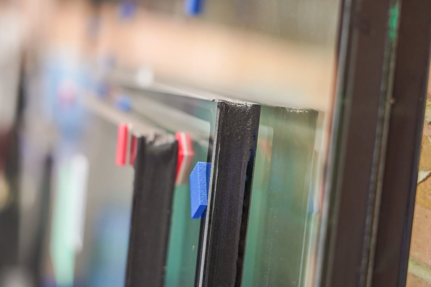 Glass panes stacked with blue and red clips. Dark frames visible.