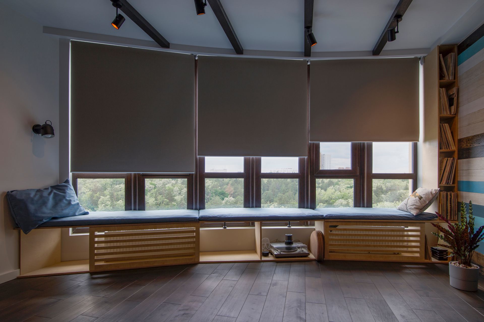 Motorized window shades lowered over three windows in a modern living room. Motorized window shades lowered over three windows in a modern living room.
