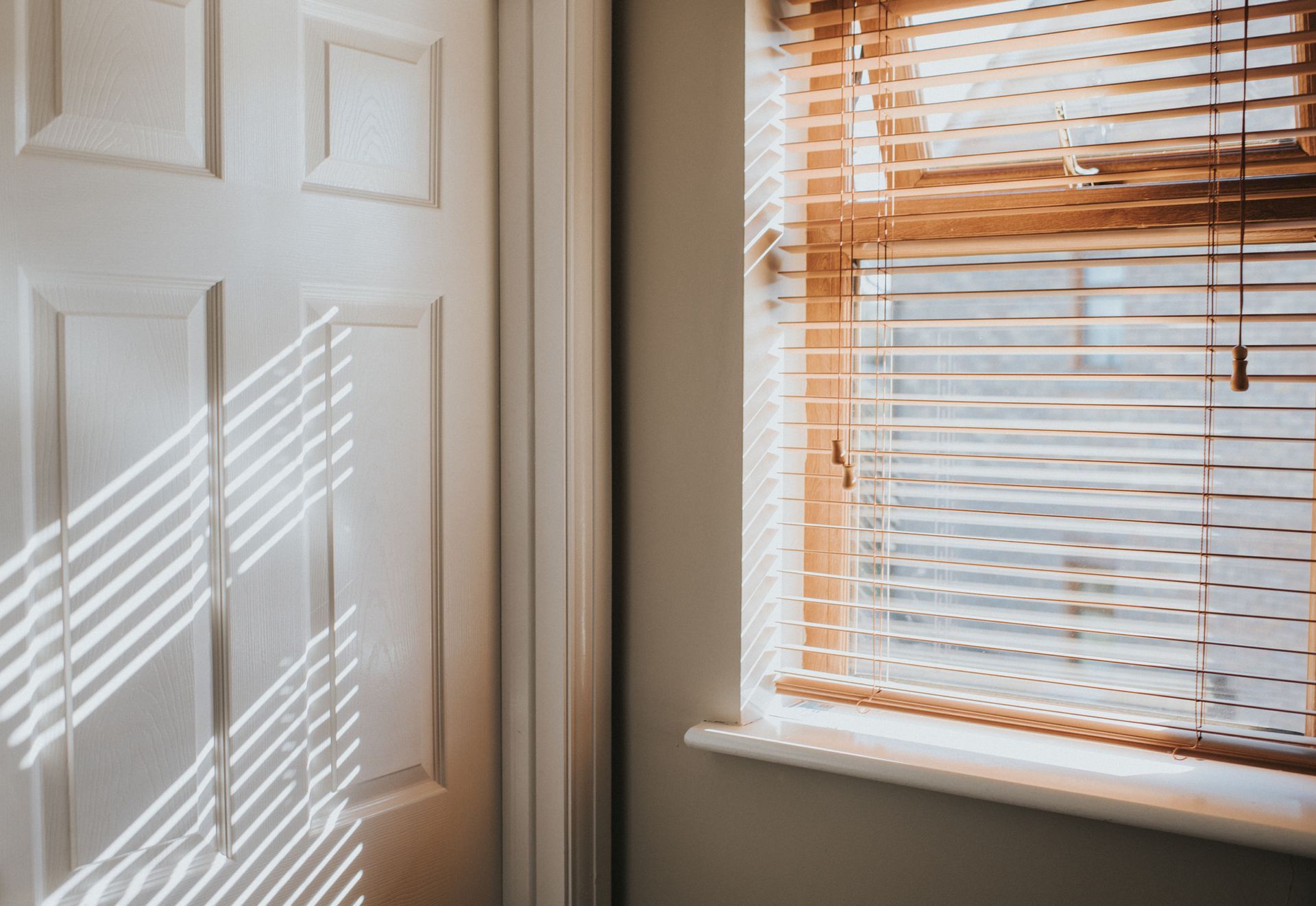 Close-up of decorative vases with dried plants on a windowsill with blinds.