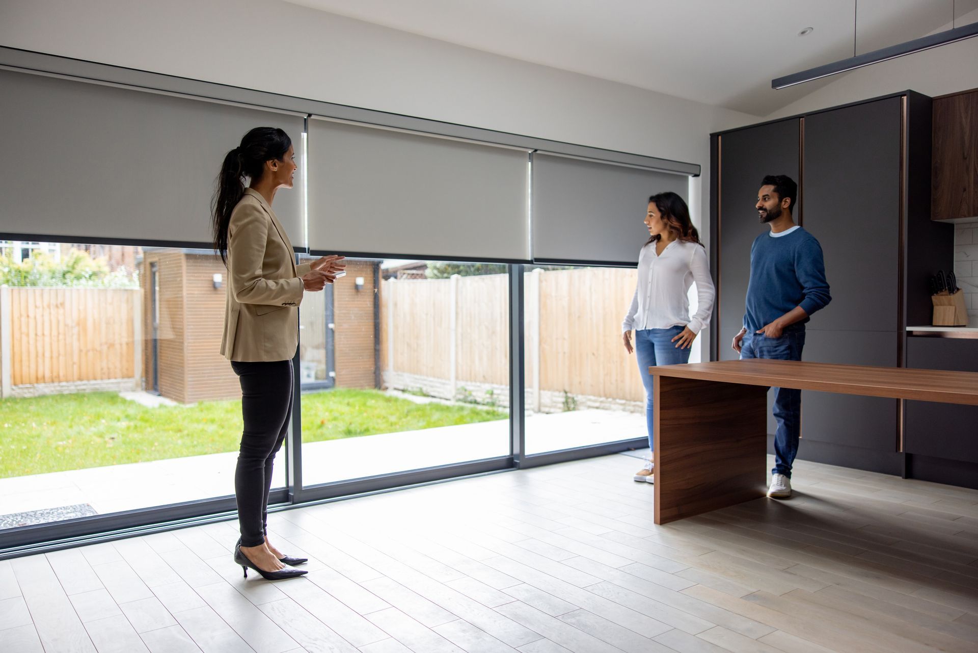 Modern living room with large windows fitted with motorized blinds partially lowered.
