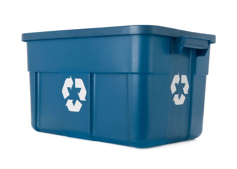 Un contenedor de reciclaje de plástico azul con dos símbolos de reciclaje.