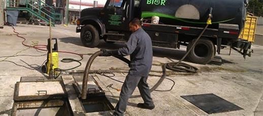 Un hombre está bombeando agua desde un desagüe hacia un camión.