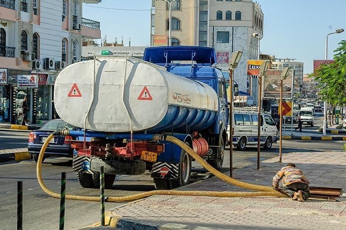 Un camión cisterna con una manguera conectada está estacionado al costado de la carretera.
