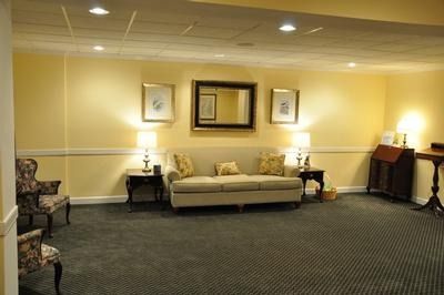 A waiting area with light yellow walls, a couch, chairs, and lamps.