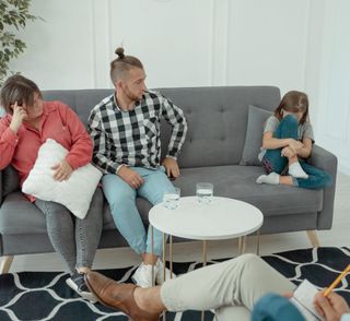 A family is sitting on a couch talking to a counselor.