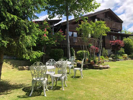 A lawn with tables and chairs in front of a house.