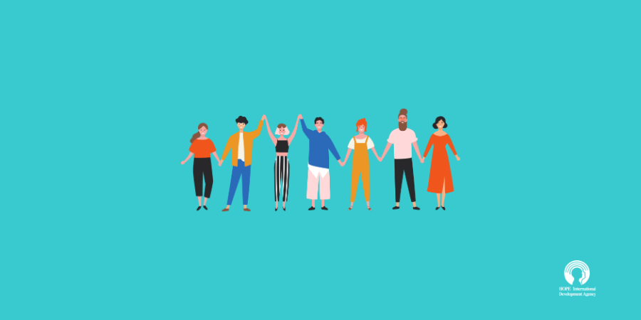 Diverse group holding hands, standing against a teal background, representing community and unity.