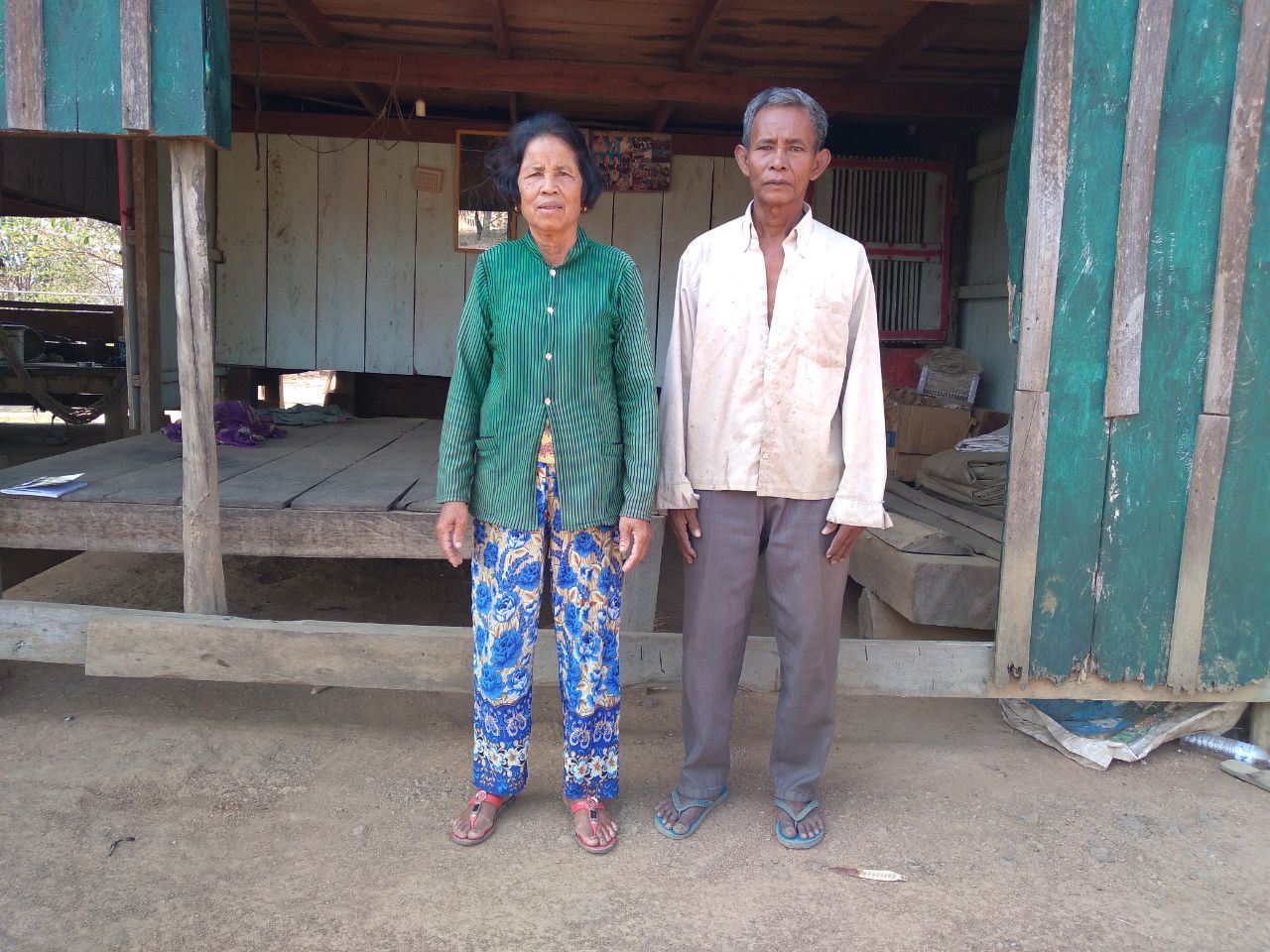 A man and a woman are standing in front of a wooden building.