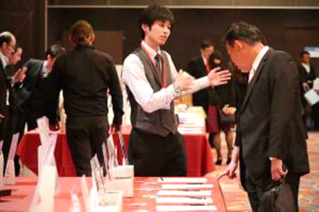 A group of people are standing around a table talking to each other.